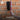 Hand holding a brush against a brick wall with a brand logo and text about professional finish.