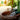 Person wearing gardening gloves top dressing a potted plant with bark chips and text about creating top dressing.