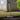 Green garden tool being used on grass with a wooden fence in the background