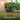 Aerator tool standing on grass with green bushes and a building in the background