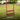 Red aerator free-standing on grass with tines penetrating the earth, text 'Greener Grass' and brand logo.