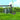 Gardening tools including a watering can and a shovel on grass with a blurred background